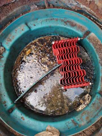 Caixa SAO com transbordamento de óleo visível na superfície, demonstrando necessidade de limpeza urgente